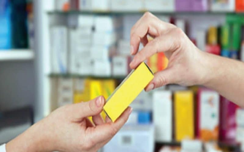 Pharmacist hands medicine to customer