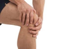 topical knee pain relief: man rubs ointment on his sore knee joint